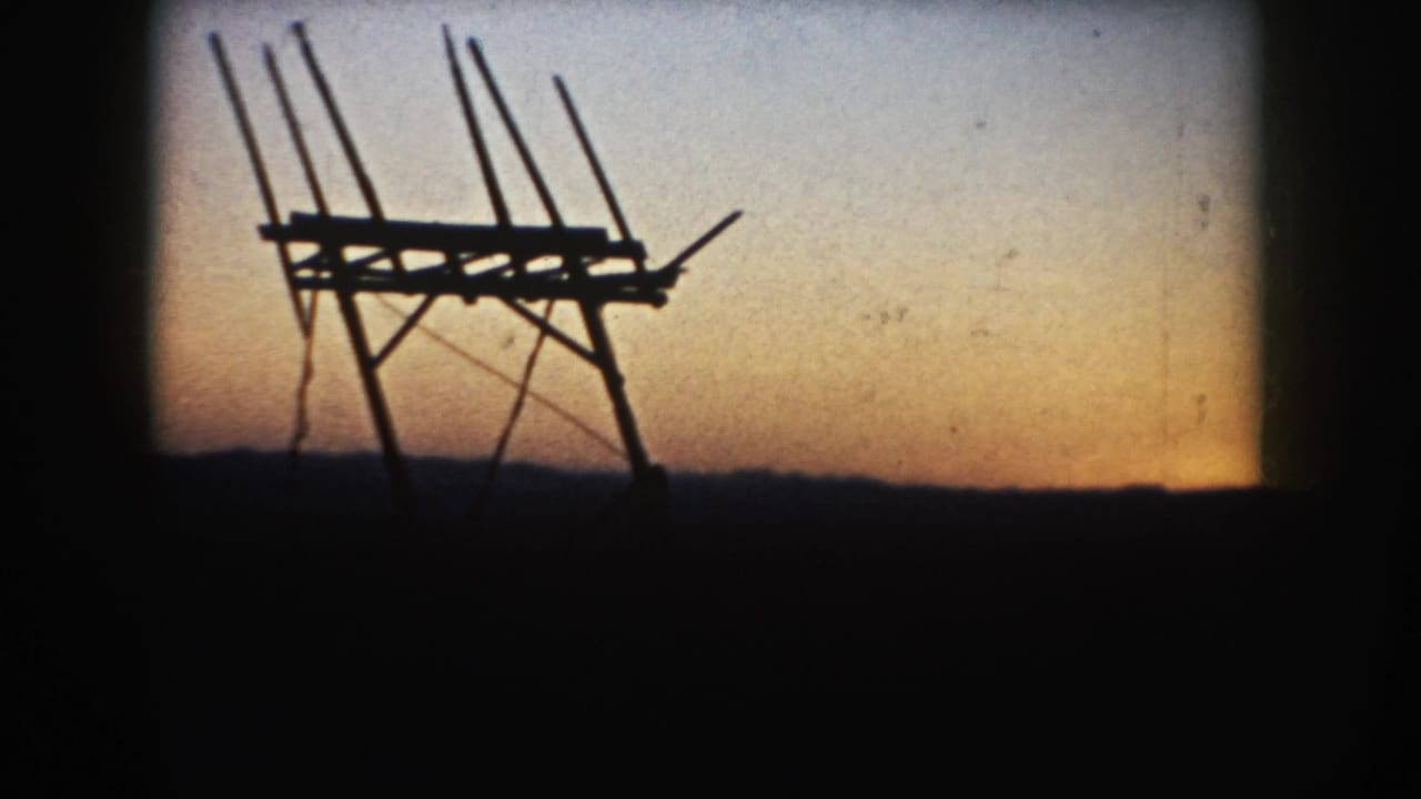 1953 South Dakota home-movie still with a black antenna-like structure silhouetted against fading orange and blue sky.