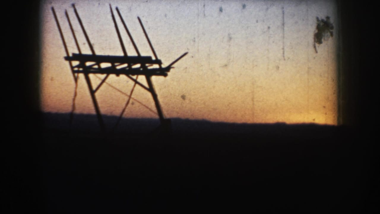 1953 South Dakota 8mm still showing the dark antenna-like structure at dusk, with dust marks and soft gate shading visible.