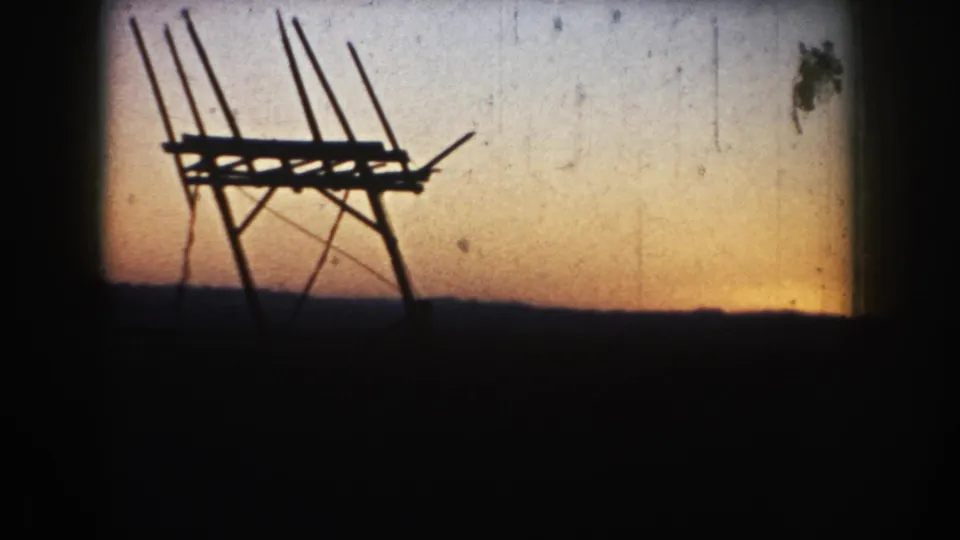 1953 South Dakota 8mm still showing the dark antenna-like structure at dusk, with dust marks and soft gate shading visible.