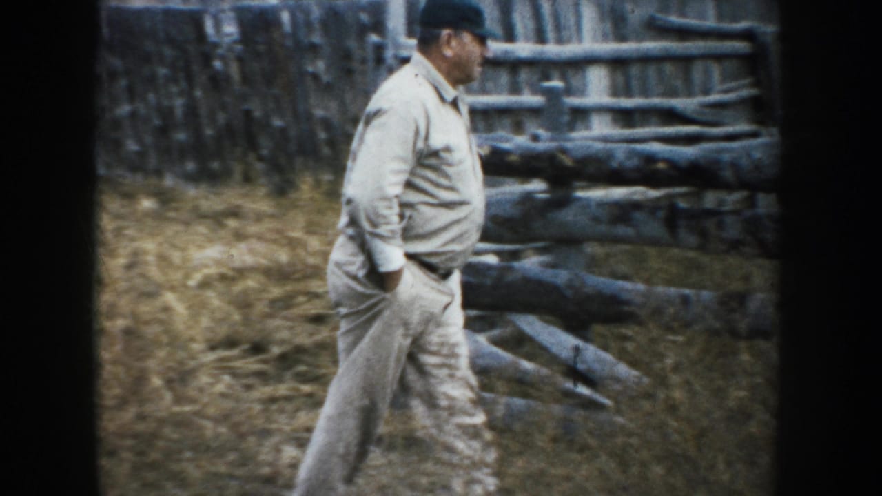 A farmer in light work clothes walks past rough rail fencing on the 1953 South Dakota farm.
