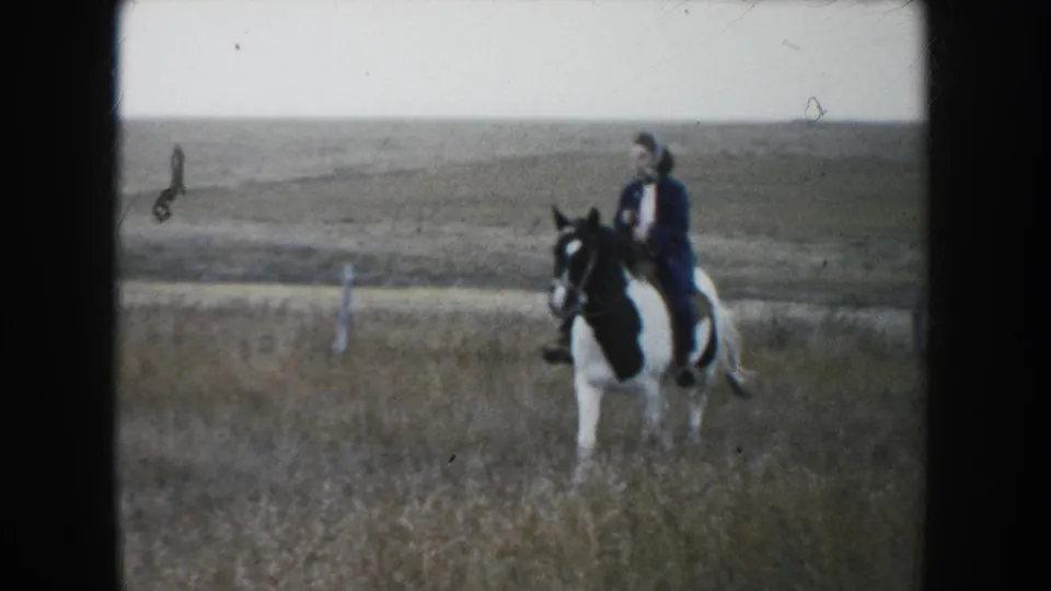 A person on horseback appears at the edge of the 1953 South Dakota prairie scene, suggesting ranch work near the moving cattle.
