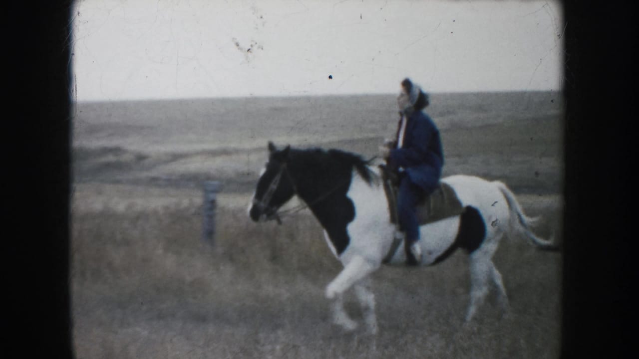Woman rider on a black-and-white pinto horse crosses South Dakota prairie in a soft 1953 8mm home-movie frame.
