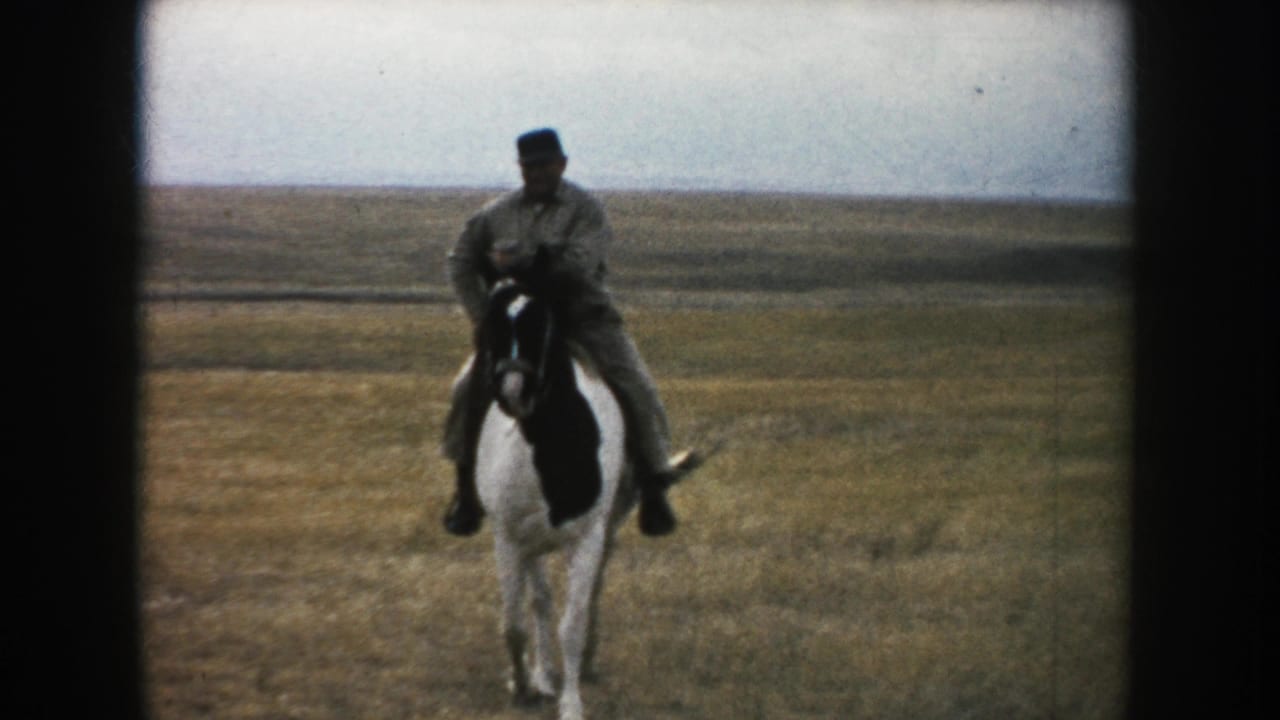 1953 South Dakota home-movie frame showing the rider and pinto horse approaching across the prairie.