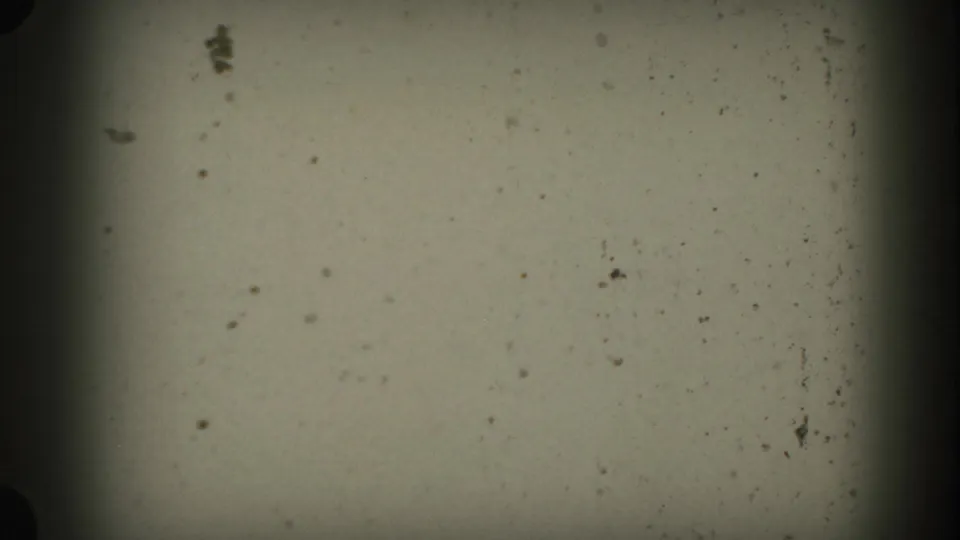 A mostly blank 1953 8mm frame with visible dust, grain, uneven exposure, and dark gate edges before the South Dakota landscape appears.