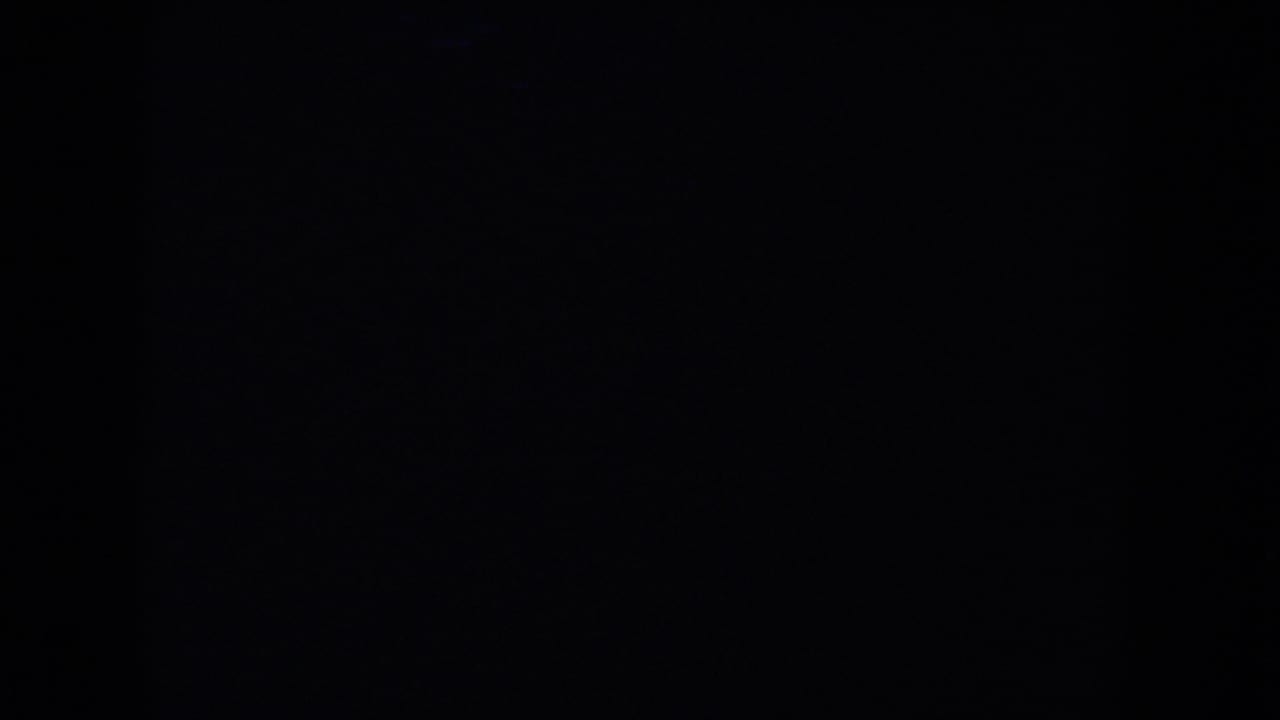 Low-light 1953 South Dakota home-movie frame with indistinct silhouetted figures under a deep blue cast.