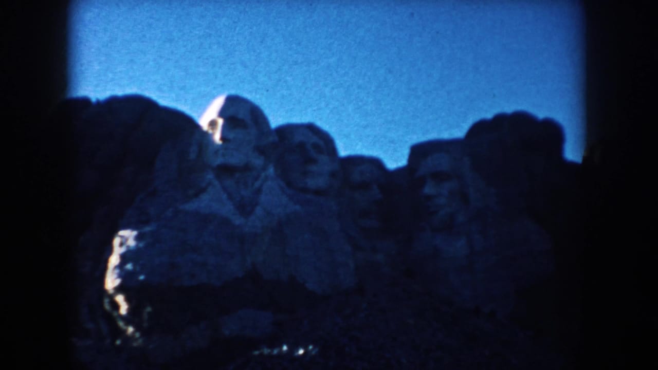 Visitor-shot 1953 8mm frame of Mount Rushmore, with the monument partly obscured by dark film-edge vignetting.