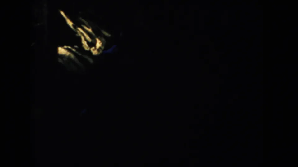 Underexposed 1953 South Dakota 8mm frame with clustered yellow streaks at lower left and barely visible surrounding shadows.