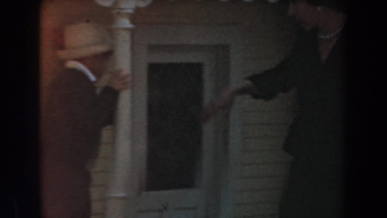 1961 Knott's Berry Farm home-movie frame showing adults moving near a white-column town-hall style doorway.