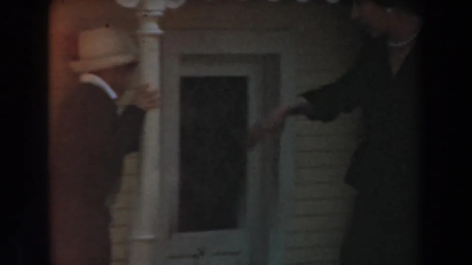 1961 Knott's Berry Farm home-movie frame showing adults moving near a white-column town-hall style doorway.