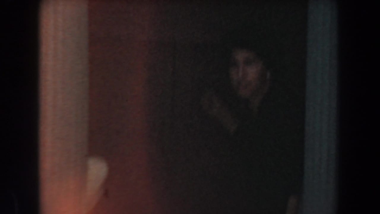 Dim interior view with a shadowed person near a doorway or partition.