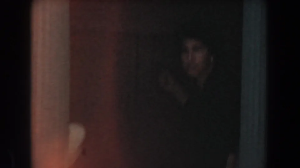 Dark 1961 Knott's Berry Farm home-movie frame with a partially visible person standing near an interior doorway or partition.