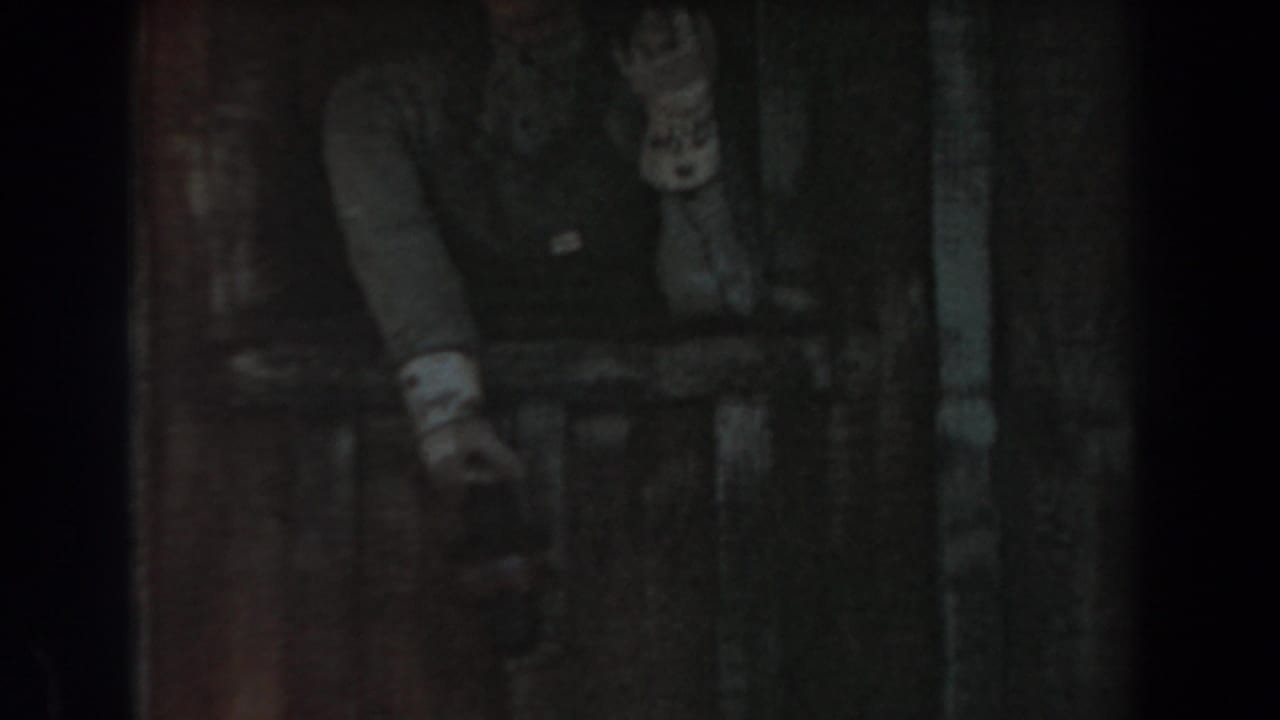 A dim 1961 Knott's Berry Farm frame shows a person partly obscured by vertical framing near the themed rail car area.