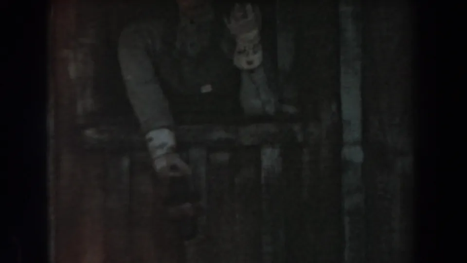 A dim 1961 Knott's Berry Farm frame shows a person partly obscured by vertical framing near the themed rail car area.