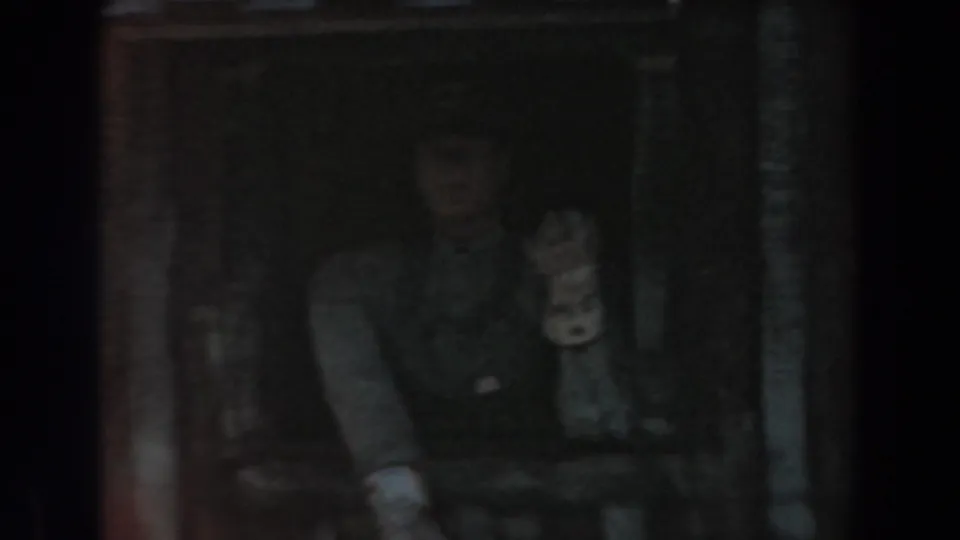 The home-movie frame shows a person in a dim Knott's Berry Farm rail setting, hand raised beside pipes and dark wooden structure.
