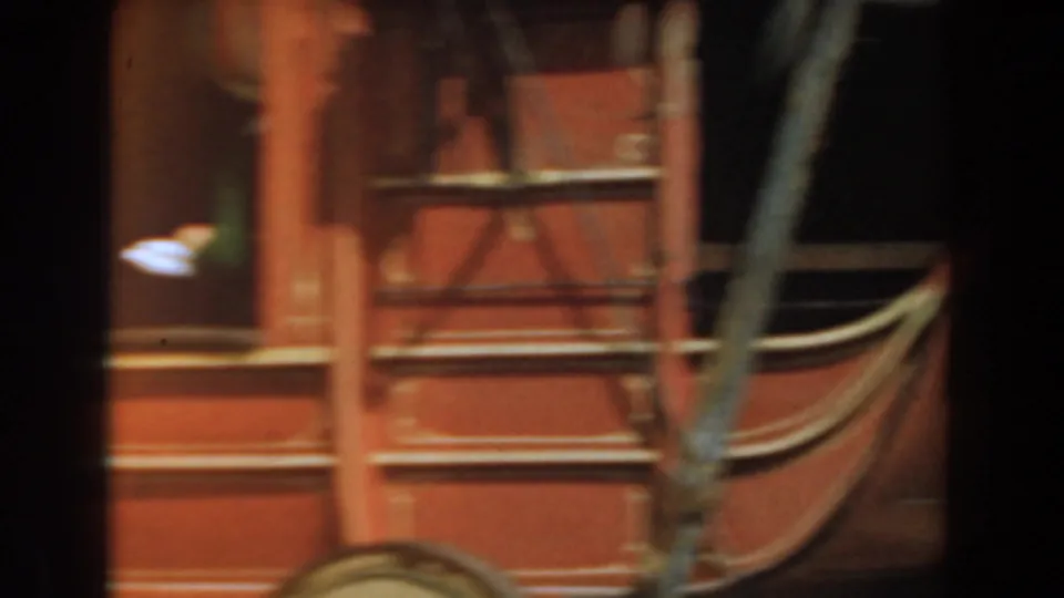 A close visitor-shot view of the red stagecoach shows the wheel, leather straps, window, and painted trim at Knott's Berry Farm.