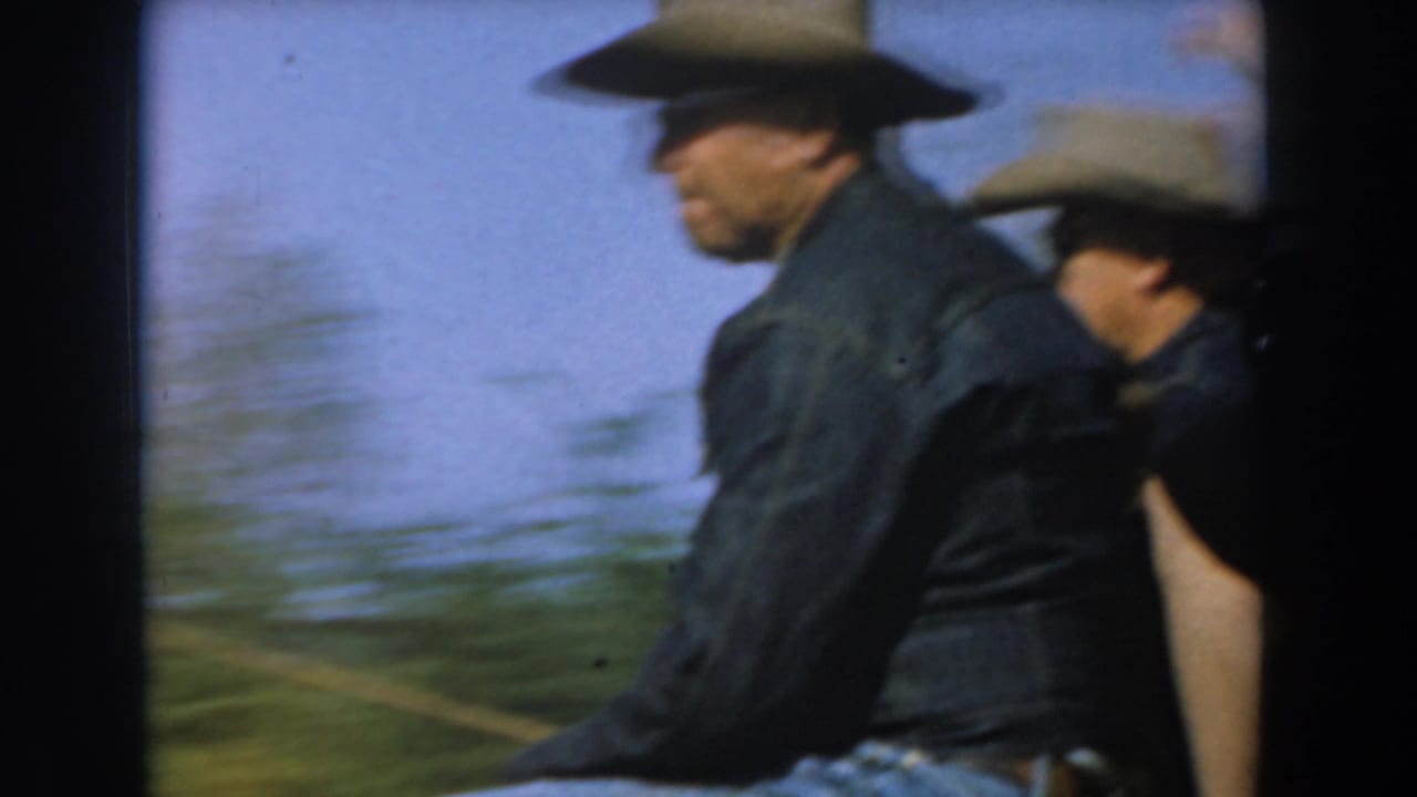 Cowboy-hatted riders seated on a moving stagecoach with blurred trees behind them.