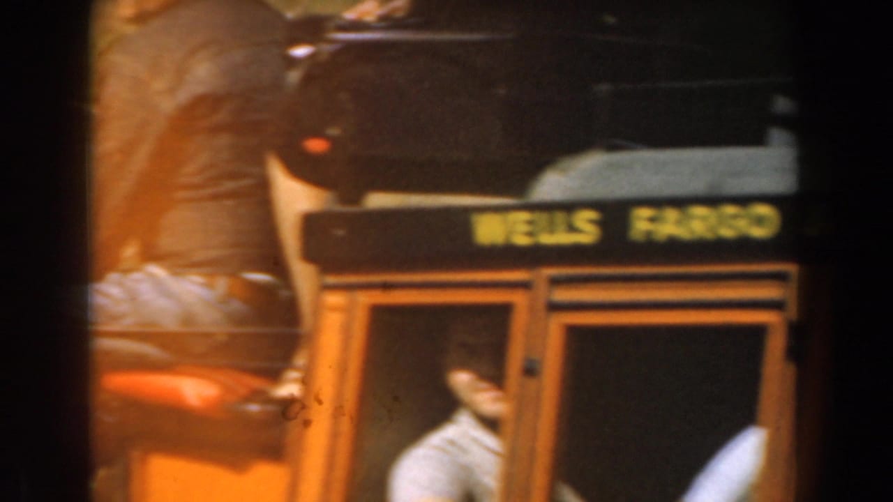 Orange stagecoach with Wells Fargo lettering and passengers visible through the window.