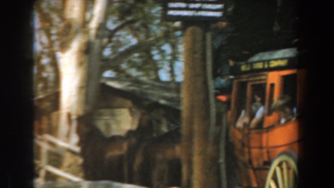 1961 Knott's Berry Farm footage showing an orange stagecoach-style carriage with passengers among trees and fencing.