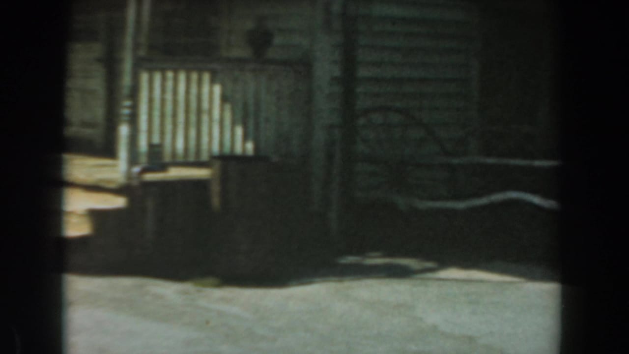 Weathered wooden Old West storefront with porch railing and a rocking chair.