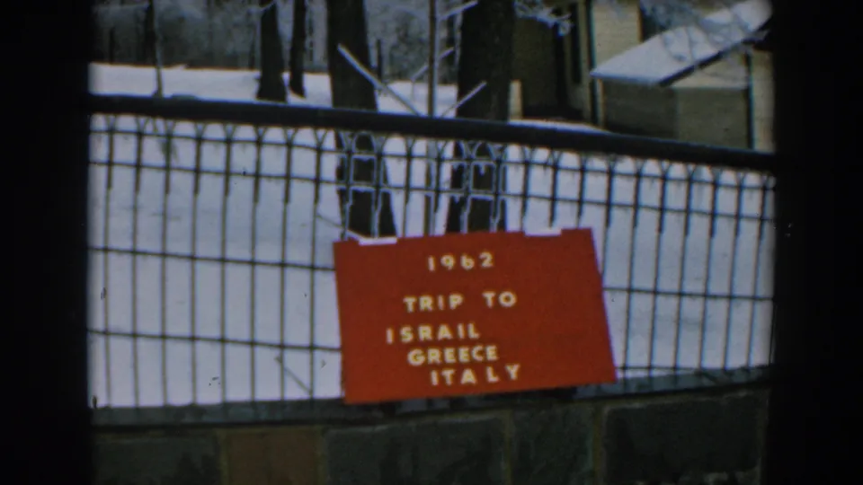 A slightly different 8mm frame shows the red 1962 trip sign on the fence, with snow and trees in the background.