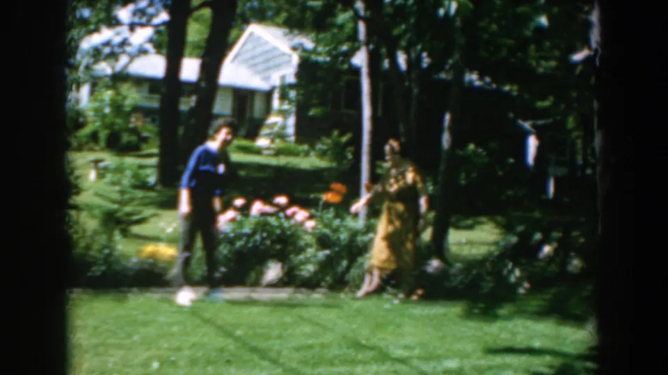 The garden view shows one woman near flowers and another walking under trees, with a house partly visible in the background.