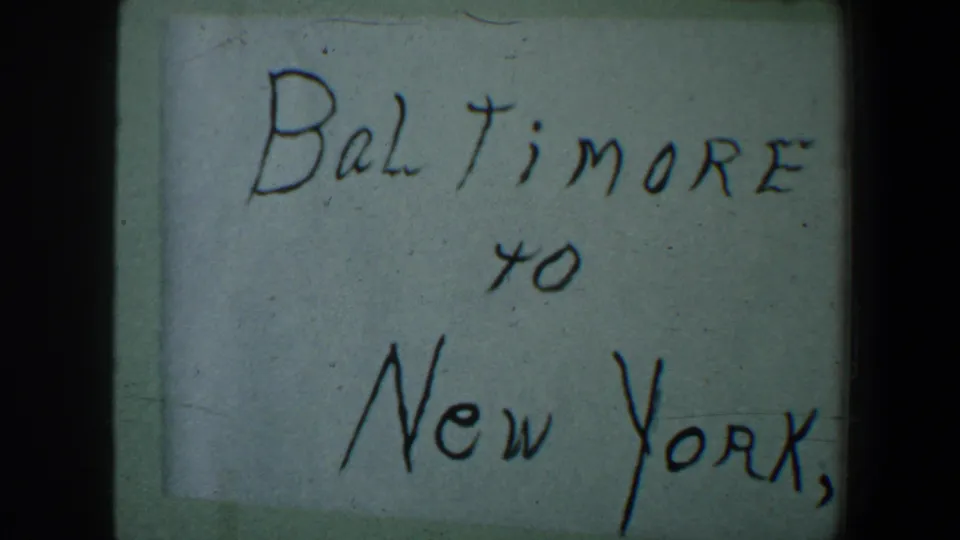 1960 8mm close-up of the handwritten Baltimore to New York, N.Y. note with soft focus and film grain.