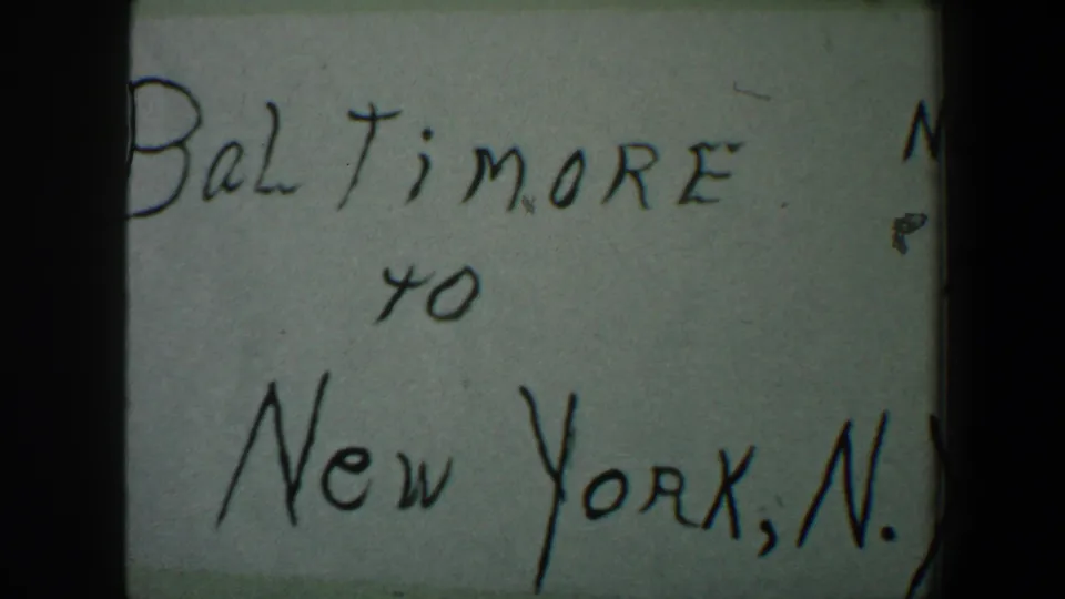 Close 8mm frame of the handwritten Baltimore to New York card, with the lower New York line most visible.