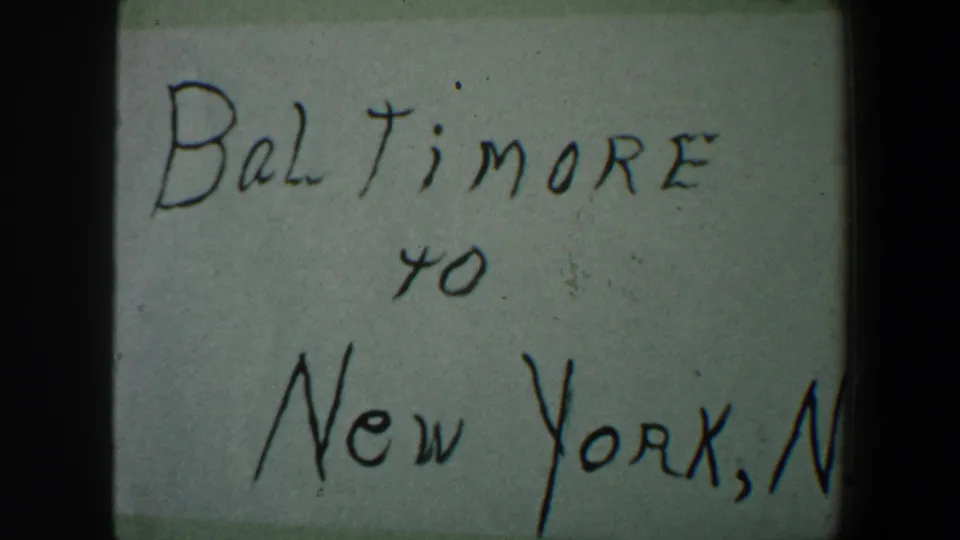 Close 8mm view of the handwritten Baltimore to New York note, with the right side cropped and visible film gate darkness.