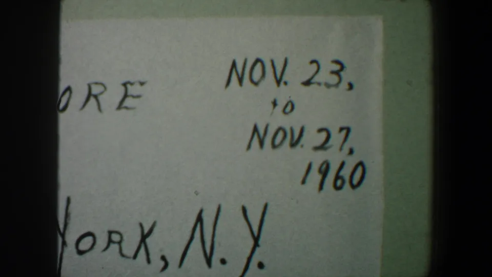 Close 8mm frame of a handwritten 1960 travel card, with Nov. 23 to Nov. 27 and New York, N.Y. partly readable.