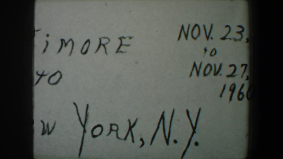 Handwritten 1960 trip card partly cropped, showing Baltimore, New York, N.Y., and November date text from an 8mm reel.