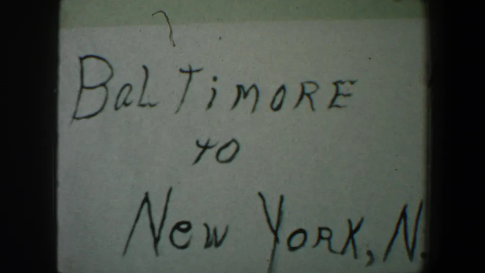 Soft 8mm frame of the handwritten Baltimore to New York, N.Y. title card, with the 1960 date range partly outside the crop.