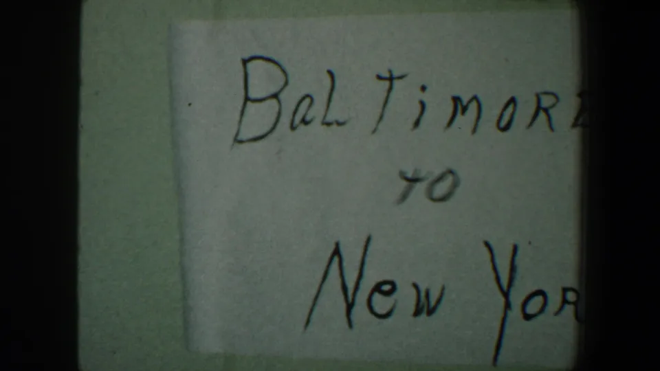 Handwritten Baltimore to New York travel card from the 1960 8mm home-movie clip, partly cropped by the film frame.