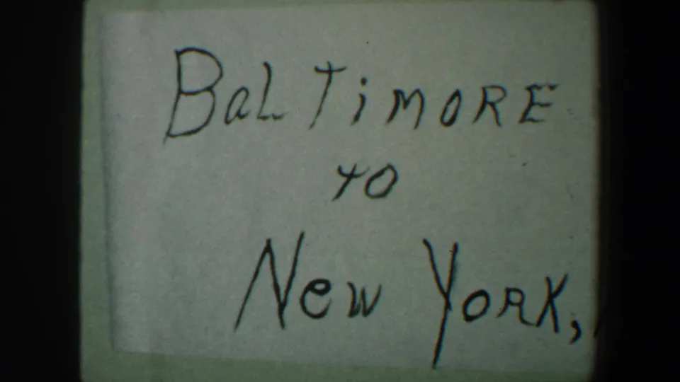 A clearer handwritten card reads Baltimore to New York, N.Y., serving as a home-movie travel title.