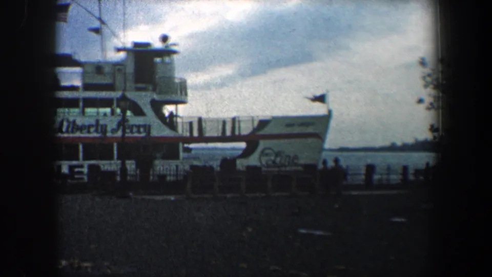 The ferry side shows Liberty Ferry lettering near a dock, with water and a cloudy sky behind it in 8mm home-movie footage.