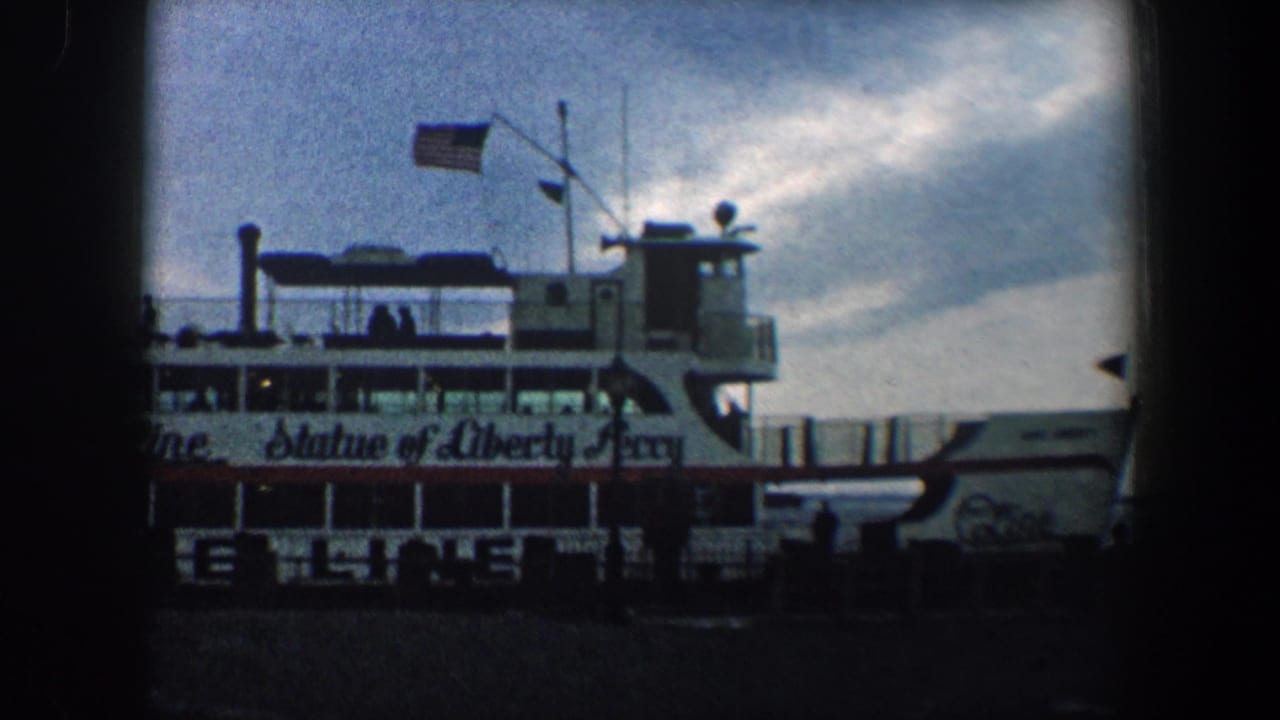 Ferry side with Statue of Liberty Ferry lettering, flags, upper deck, and dock foreground.