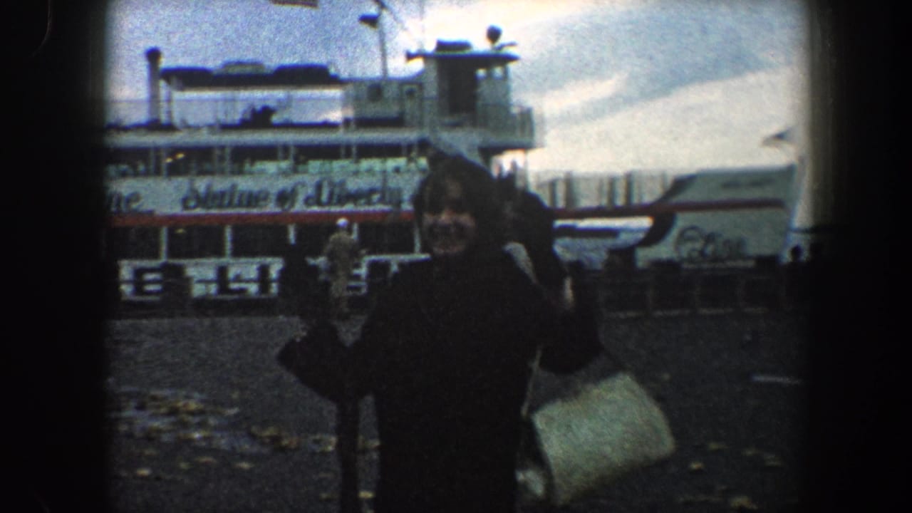 In 1960 New York City, a woman waves toward the camera beside a ferry marked Statue of Liberty Ferry.