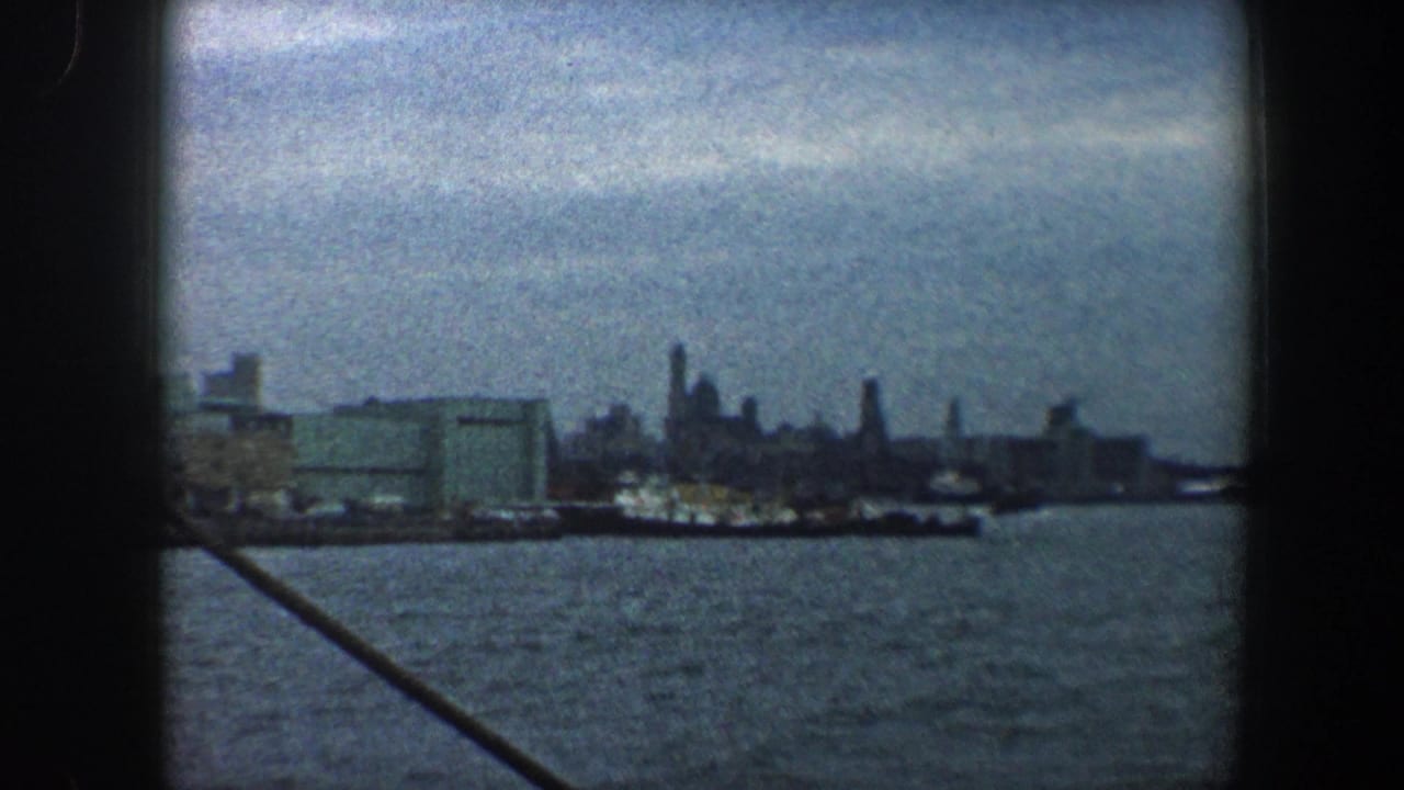 Harbor water and distant city skyline seen from a moving boat.