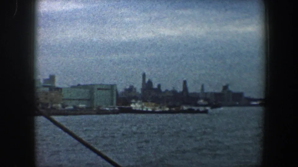 New York City harbor view from a boat, with water in the foreground and a distant skyline across the frame.