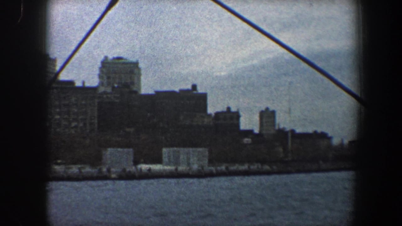 City waterfront and skyline behind a dark vertical frame edge and diagonal cable.
