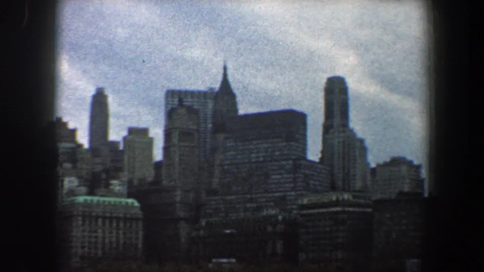 1960 New York City skyline seen from across the water, with dense high-rises in soft 8mm color.