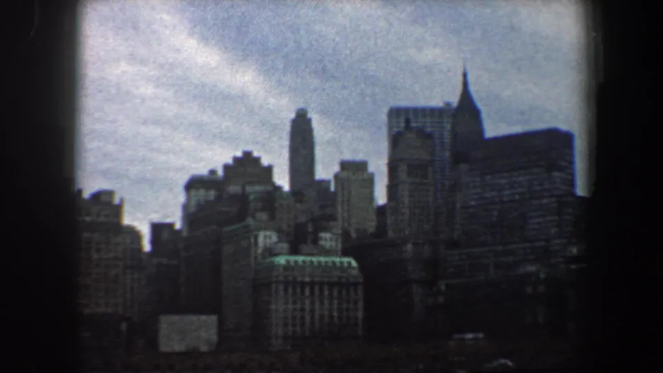 The camera pan shows a dense 1960 New York City skyline with varied tower shapes and dark waterfront foreground.
