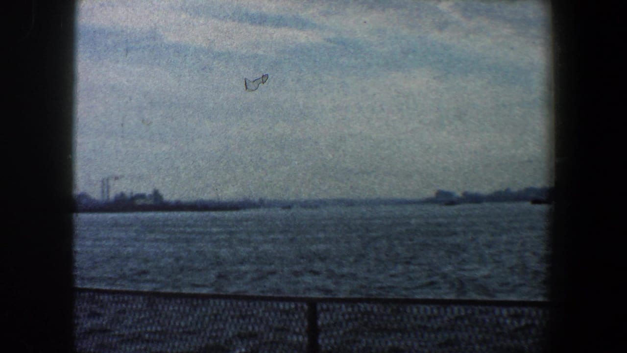 Wide harbor view with distant buildings and a dark vertical frame divider.