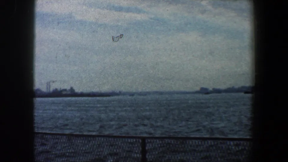 Distant New York City waterfront seen across the harbor, with soft skyline shapes and 8mm gate borders.