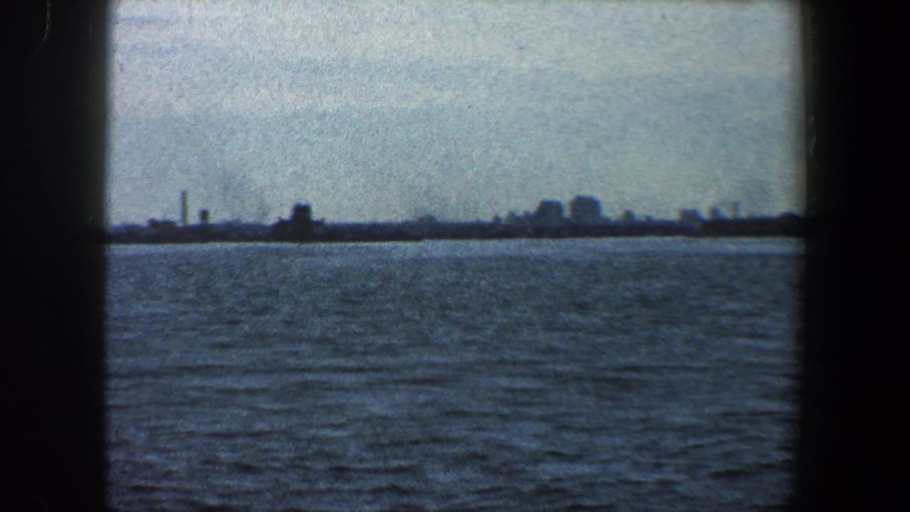 Wide water view with a far urban horizon and faint industrial structures.