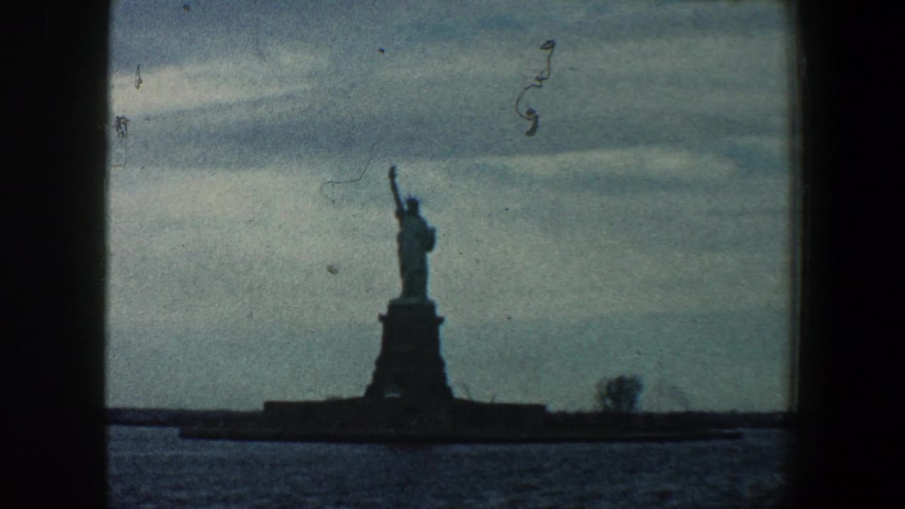 Statue of Liberty seen from across the water with dark borders and muted sky.