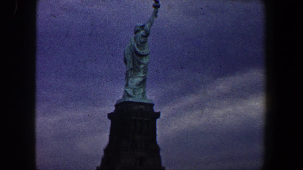 Statue of Liberty upper body and pedestal against a dark cloudy sky.
