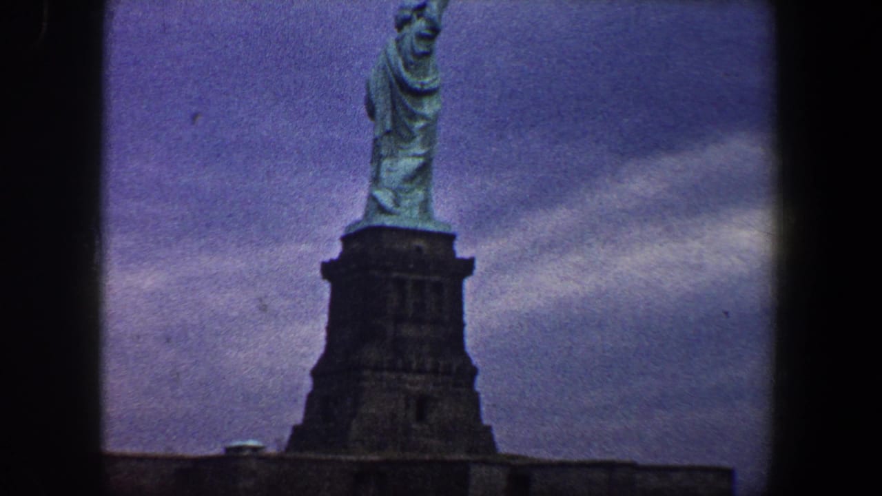 Statue of Liberty and pedestal centered with cloudy sky behind.