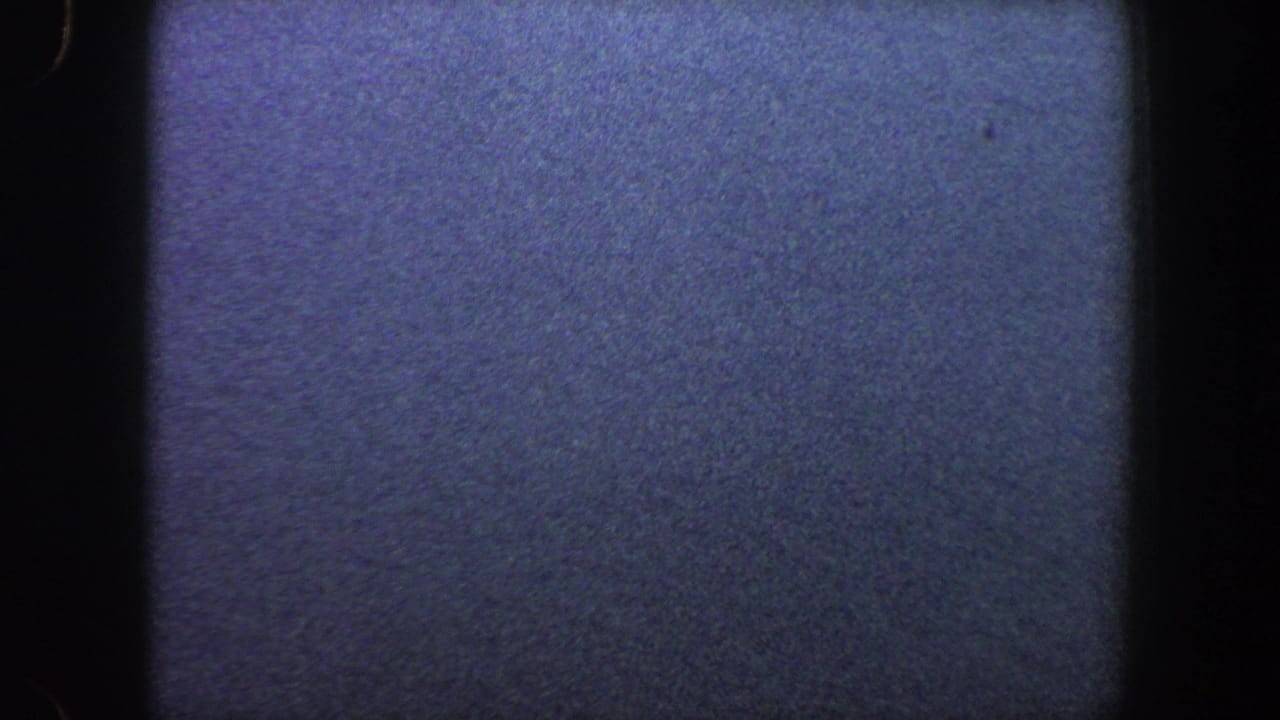 Grainy blue-gray field with faint horizon texture and dark film border.