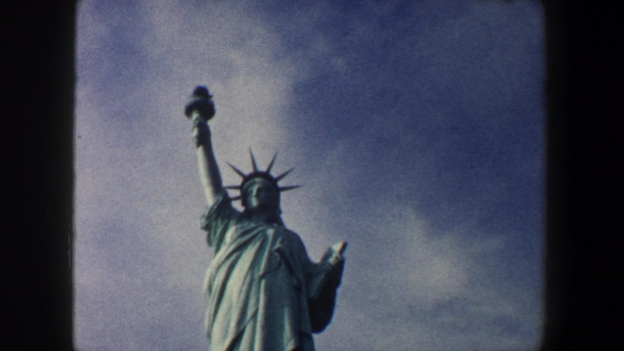 Statue of Liberty upper body and torch seen from a low angle under clouds.