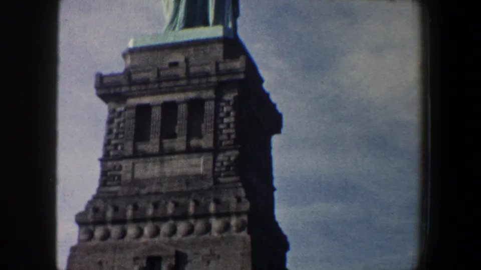 1960 New York City 8mm frame focused on the Statue of Liberty pedestal, with the statue partly cropped at the top.